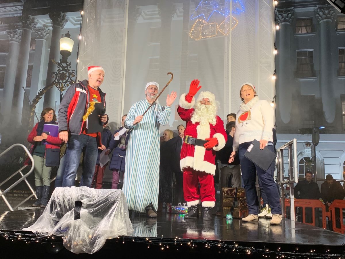 Scrooge on stage with Santa and presenters from BBC Radio Glos